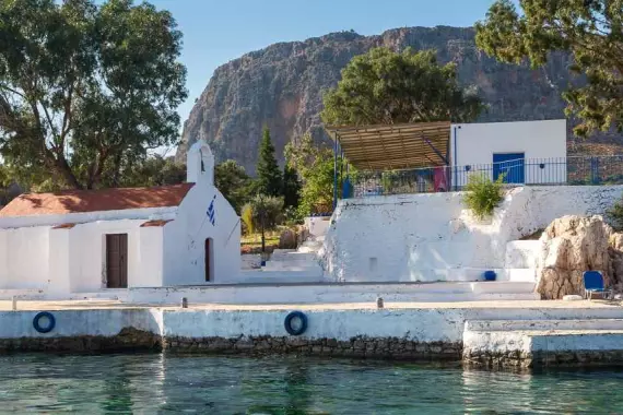 Isola di Kastellorizo: panorama con chiesa e casa sul mare trasparente del Dodecaneso